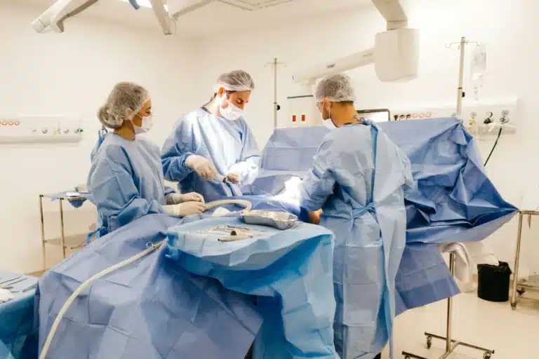 Surgeons wearing disposable ppe while operating on a patient.