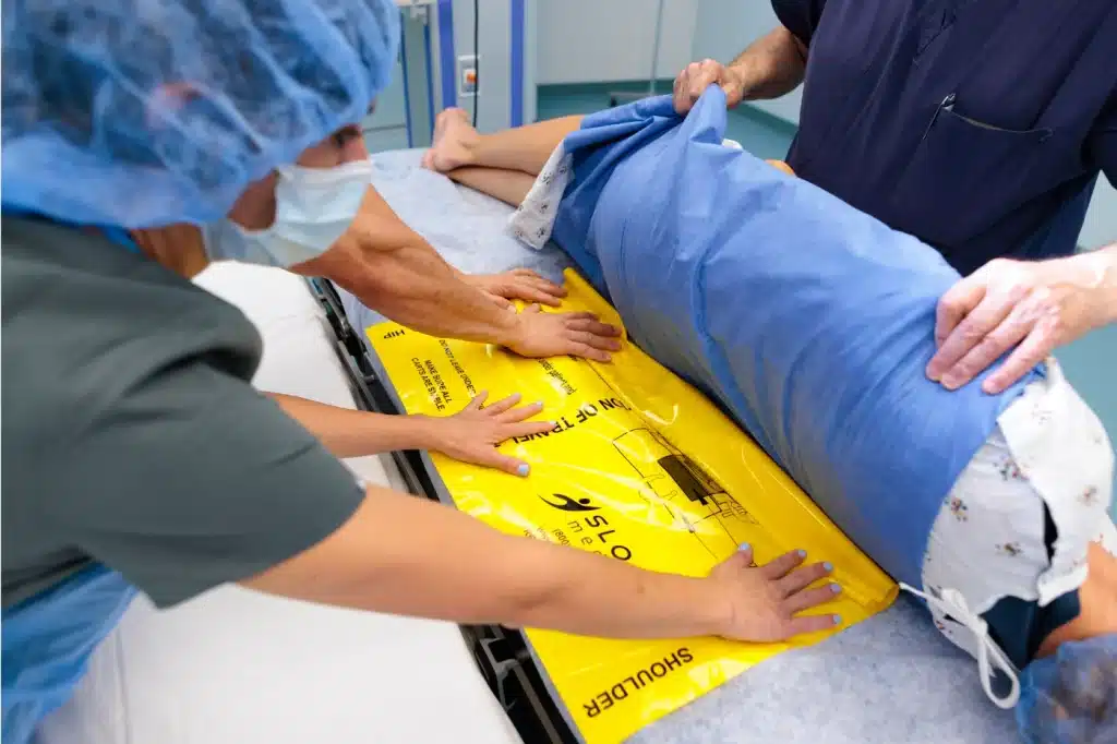 Medical professionals moving a patient with a disposable patient transfer sheet